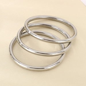 Detailed view of three polished silver hollow stainless steel bangles set on white background