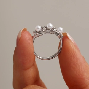 Stainless steel open ring featuring three white pearls on a polished silver band