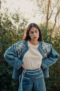 Detailed view of the intricate white floral embroidery on a vintage blue denim quilted jacket