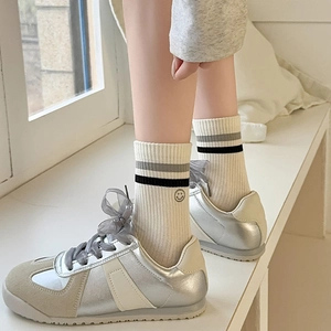 Casual silver athletic shoes paired with cream striped crew socks featuring a smile embroidery