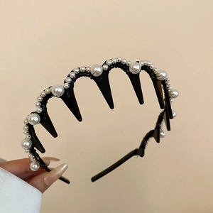 Macro shot of wavy toothed black headband with elegant white faux pearls and rhinestones