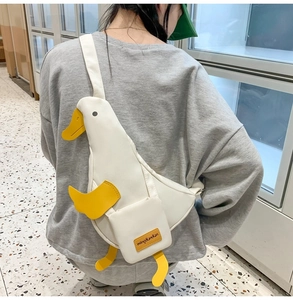 Detail of cute white cartoon duck crossbody bag with yellow feet on a grey sweatshirt