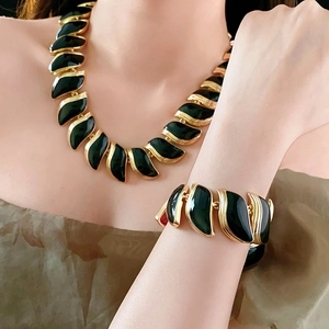 Détail du collier et bracelet vintage à feuilles noires portés au cou et au poignet