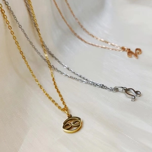 Detailed macro view of zodiac necklaces in gold, silver, and rose gold on white silk
