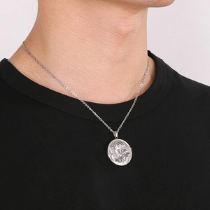 Vue détaillée du pendentif croix Saint-Benoît argenté porté sur un t-shirt noir