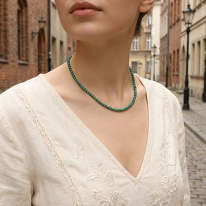 Detailed close-up of emerald green beaded necklace with gold spacers on a model