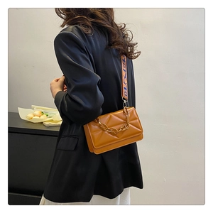 Brown quilted crossbody bag with chunky chain detail and printed fabric strap on a model