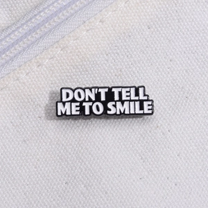 Detail of Don't Tell Me to Smile enamel pin on canvas fabric for casual style