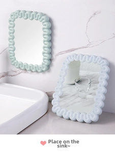 Detail of wavy frame makeup mirror in mint green and light blue for desktop use