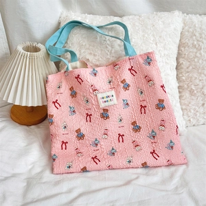 Detail of pink pleated canvas tote bag with cute animal patterns and blue handles