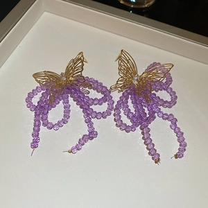 Detail view of golden butterfly earrings with purple crystal tassel fringe and rhinestones