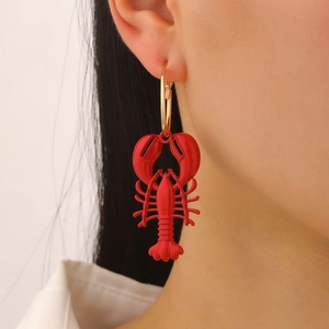 Detailed close-up of a vibrant red lobster enamel earring worn on a model's ear
