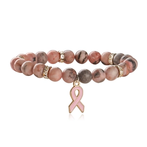 Pink agate beaded bracelet with ribbon charm and crystal accents on white background