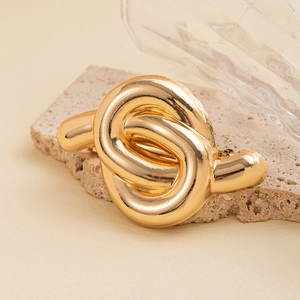 Detailed view of the chunky gold knotted metal hair tie on a decorative stone base