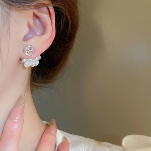 Detailaufnahme eleganter cremefarbener Blumenohrringe mit Zirkonia am Modell