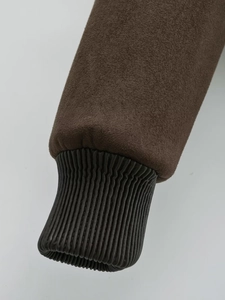 Detailed close-up of brown suede fabric and black ribbed cuffs on a winter jacket