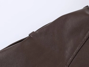 Macro shot of dark brown faux leather texture and fine stitching on the jacket collar