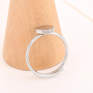 Detail of silver heart-shaped adjustable ring displayed on a wooden stand