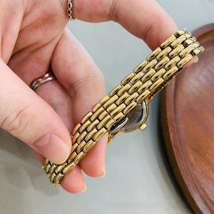 Detail of elegant gold chain strap and stainless steel case back of a mini vintage watch