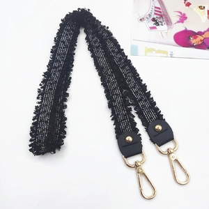 Detail of black and white woven embroidery strap with fringe and gold lobster clasps