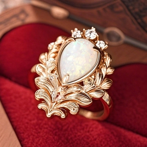 Detail of vintage baroque ring with pear-shaped opal and gold leaf texture on red velvet