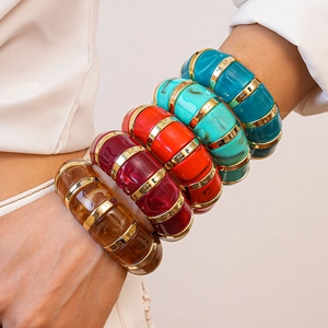 Detail of stacked acrylic cuff bracelets with gold metal joints and vibrant marbled patterns