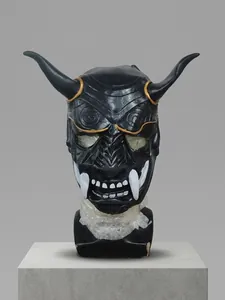 Detailed view of a black Hannya mask featuring golden eyes and sharp white resin tusks