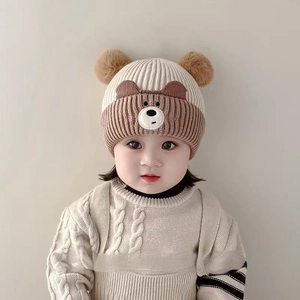 Detail of baby winter knit hat with bear face embroidery and dual fluffy pom pom ears