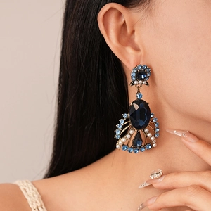 Close-up of model wearing vintage gold earrings with blue stones and pearls