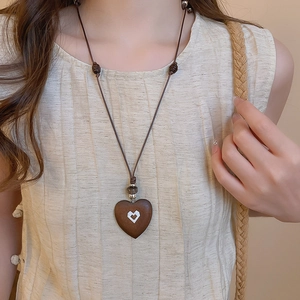 Close-up of vintage heart-shaped wooden pendant necklace on cotton linen clothing