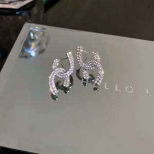 Macro shot of silver stud earrings featuring interlocking design with micro-paved zircons