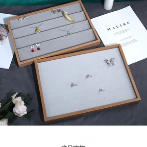Macro view of wooden jewelry display trays with grey velvet lining for rings and necklaces