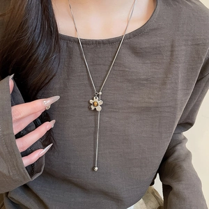 Detail shot of a silver Y-shaped necklace with a floral tiger eye stone pendant on a model