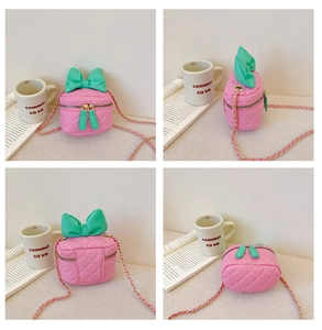 Detail view of pink quilted handbag with green bow, gold chain, and dual zipper closure