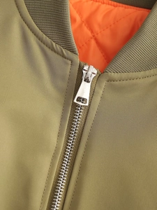 Close-up of olive green bomber jacket with orange quilted lining and silver metal zipper