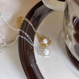 Detailed close-up of heart pearl pendants in gold and silver S925 silver on ceramic