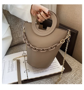 Detail of khaki PU leather bag featuring a round handle and thick decorative chain