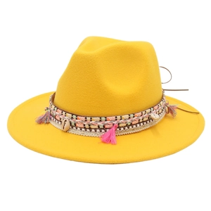 Detail of yellow wool felt fedora with colorful tassels and natural shell ornaments