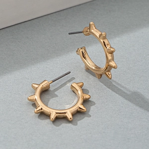 Macro shot of gold punk hoop earring with rivets and spiked metallic textures