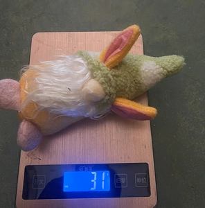 Detail showing weight of Easter gnome plush with rabbit ears on a digital scale