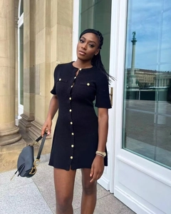 Detail of black knit mini dress with gold buttons and vintage style crew neck