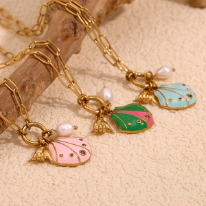 Close-up of 18K gold plated shell and Shaka hand pendants with pearls on a branch