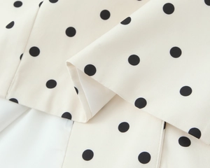 Vue macro détaillée d'un tissu beige avec motif à pois noirs et texture soyeuse et fluide