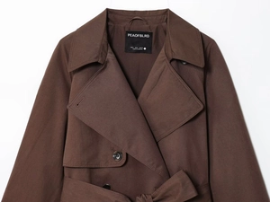 Close-up of dark brown double-breasted trench coat with wide lapels and belt details
