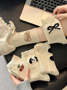 Detail of cream cotton socks with colorful flecks and cute bear and bow embroidery