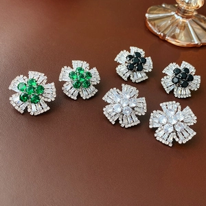 Detailed view of flower stud earrings in emerald green, black, and white on leather