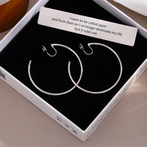 Polished silver large hoop clip-on earrings displayed in a black velvet jewelry box