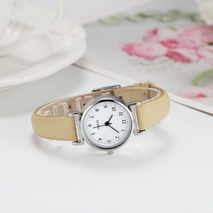 Macro detail of minimalist women's quartz watch with cream strap and numeric white dial