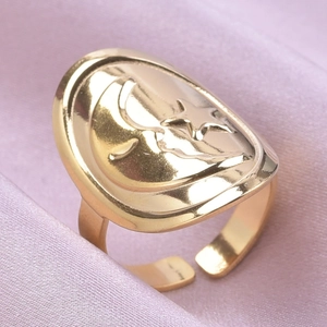 Gros plan d'une bague céleste dorée avec relief lune et étoile sur fond de soie douce