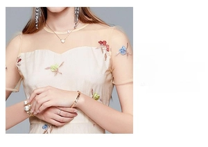 Detail of colorful floral embroidery and sheer mesh neckline on apricot dress